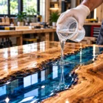 Clear epoxy resin being poured onto a live-edge wood table for a glossy river table finish.toolstationpakistan, tollstation.com