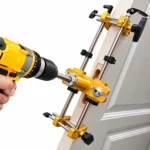 Adjustable gold alloy door mortising and drilling jig mounted on a wooden door with steel guide rods, clamps and cutter bits.toolstationpakistan, toolstation.com